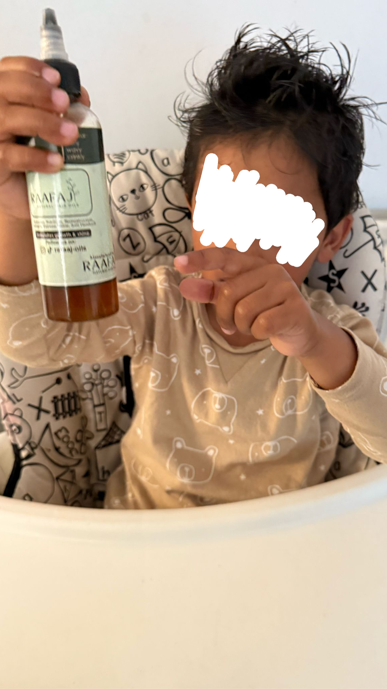 A young boy holding the hair oil bottle